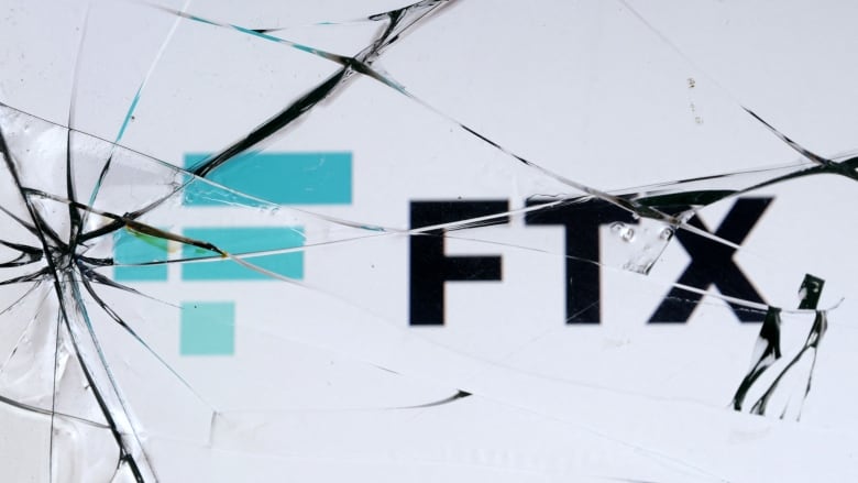 Black letters spell out FTX underneath a pane of cracked glass. There are blue rectangles next to FTX as part of the logo design. 