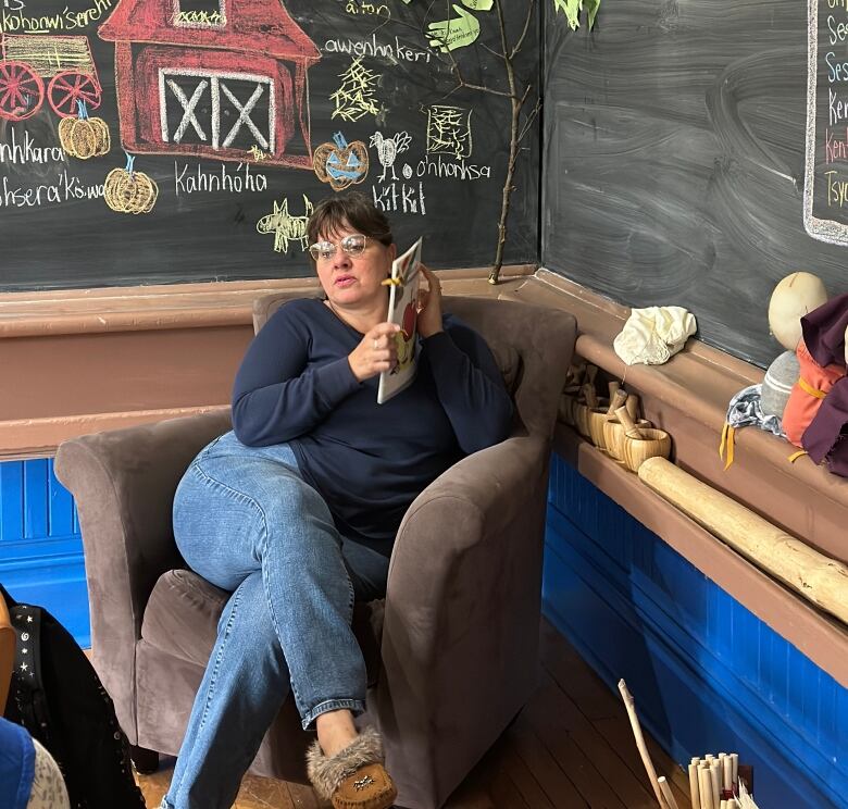 Teacher sitting in a chair, reading to students.