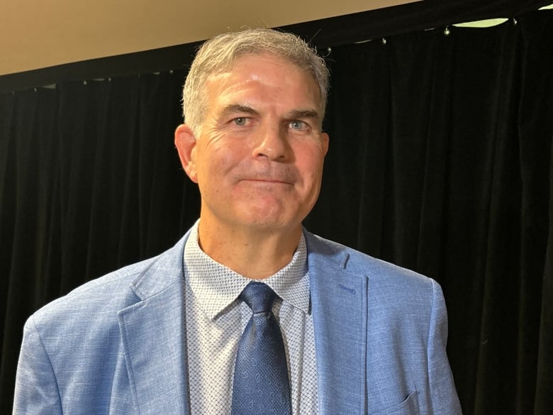 A white man with white hair, wearing blue suit.