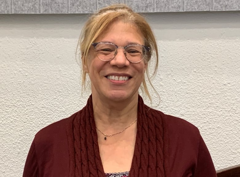 Woman wearing red sweater smiling at camera.