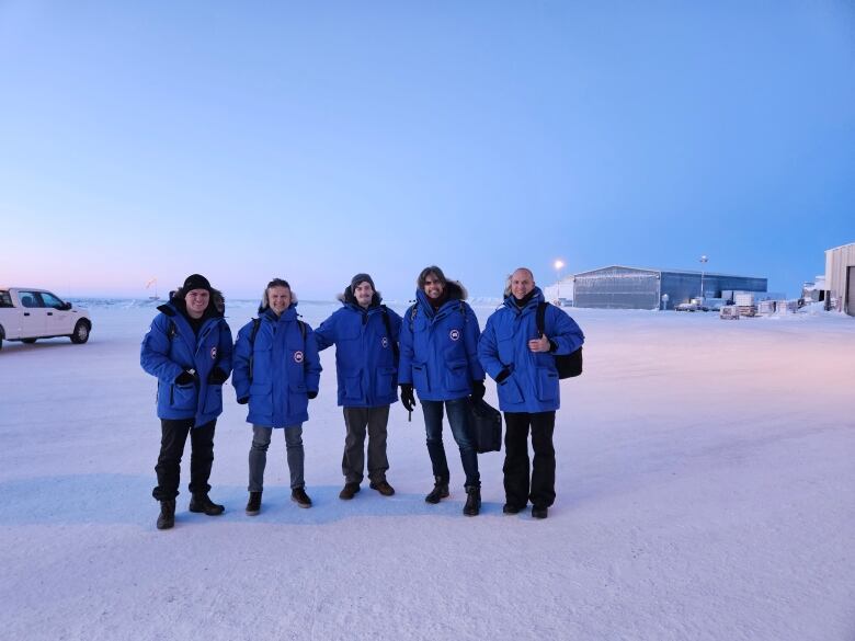 Team of scientists in parkas standing on the ice. 