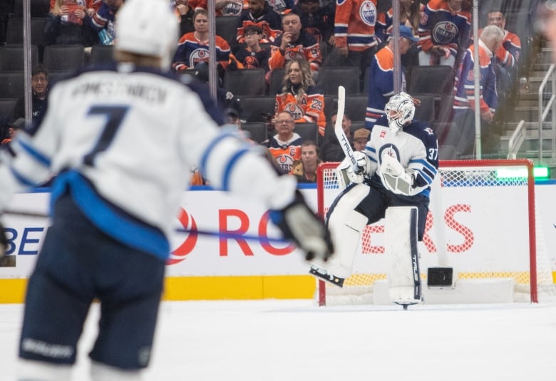 A hockey goalie lifts a leg and pumps his arms in celebration of a win.