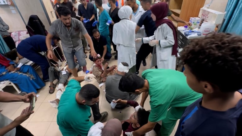 Health-care staff stand in a crowded room full of wounded Palestinians.