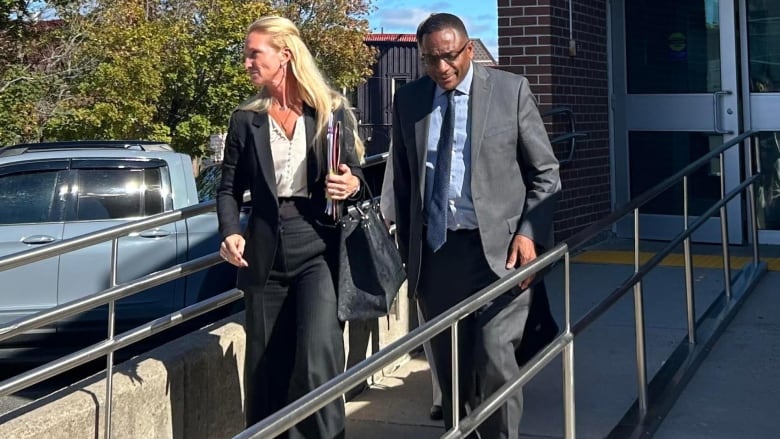 Photo of a man and a woman in a suit outside a courthouse