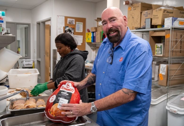 Two people stand in a kitchen with turkey.