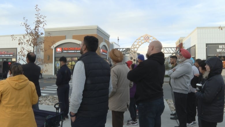 A group of people standing outside in a mall parking lot.