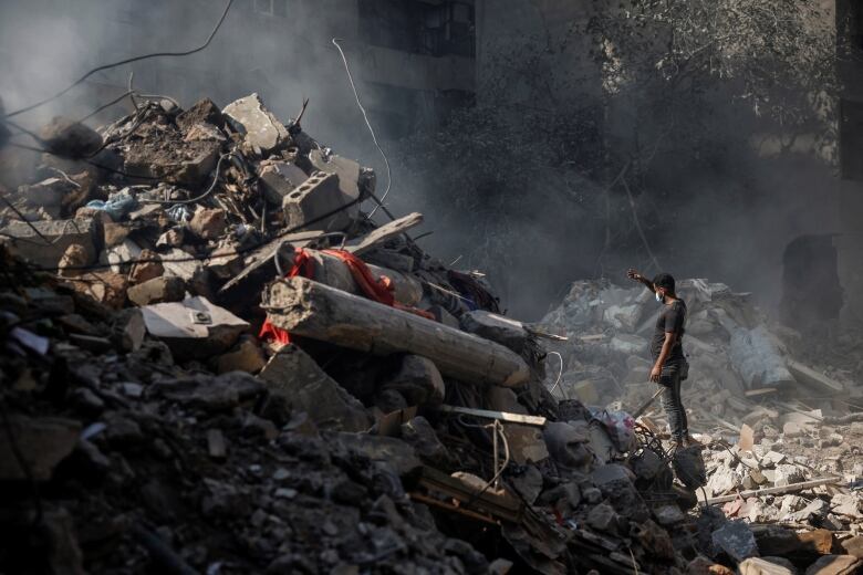 A man looks at a mountain of rubble.