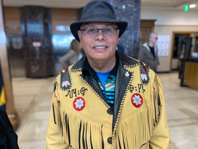 Man in hat and yellow jacket smiles