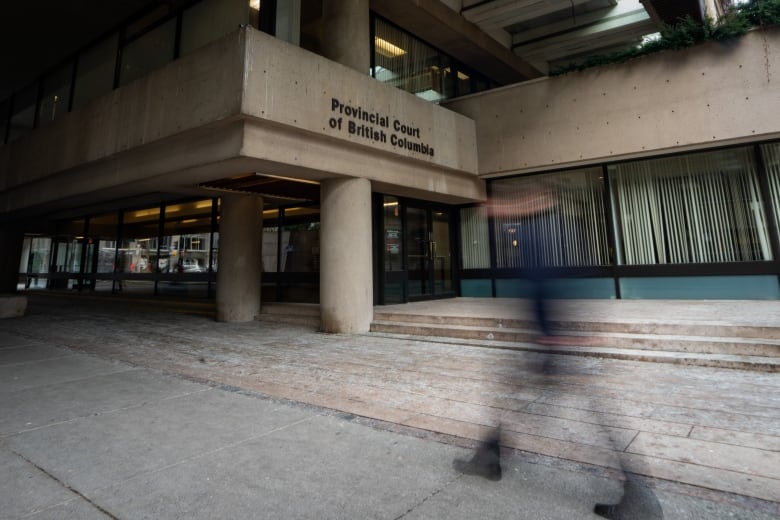 A blurred photo of a man passing by through a court house.