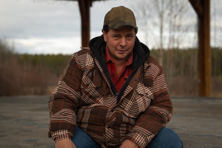 A man sits on a gazebo. 