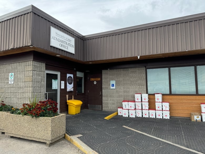 A brick building with piles of jugs outside. 