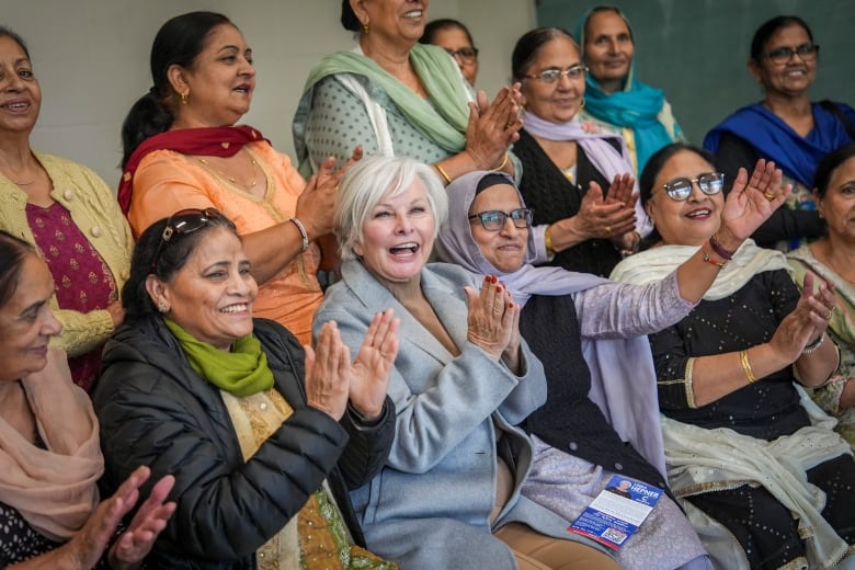 A group of women and seniors smile and clap their hands