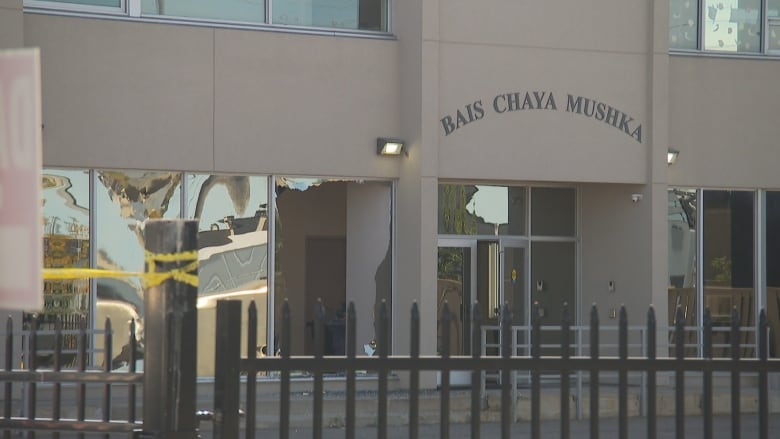 Police tape is up in front of a Jewish school on a city street on a fall day