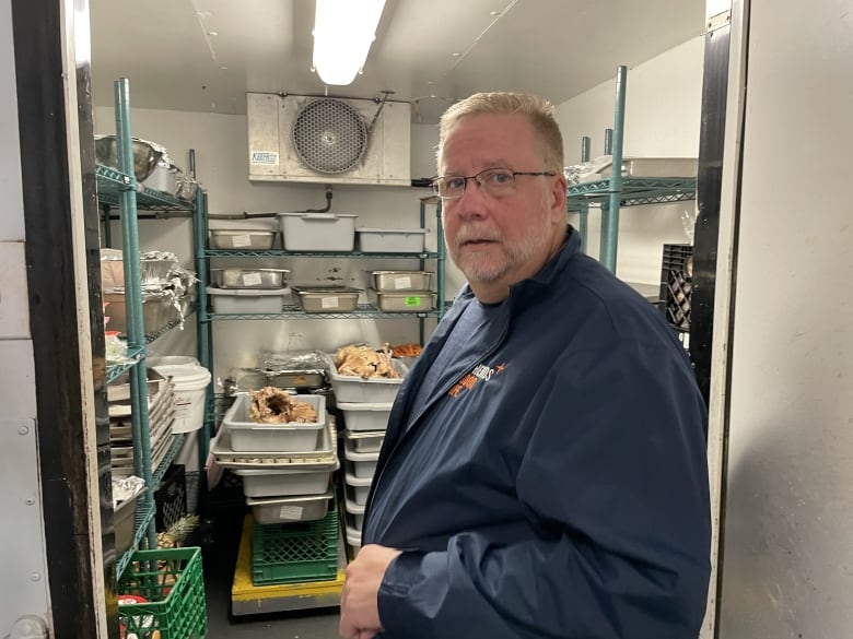 A Man standing in a walk-in refrigerator containing Thanksgiving turkeys