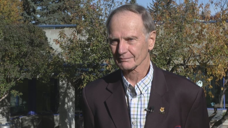 A man wearing a jacket and a striped shirt.