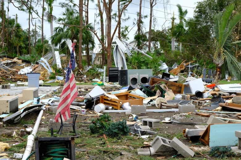 An American flag stands among the rubble of a home destroyed by a tornado.