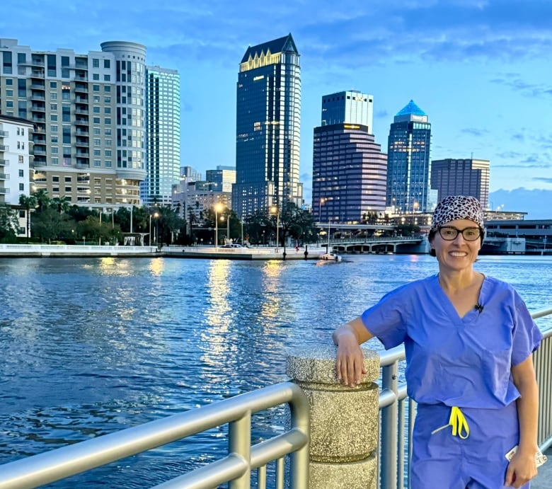 A woman smiles in front of a bridge.