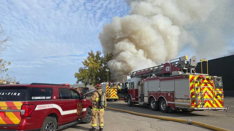 A firetruck and firefighter looking at a structure on fire