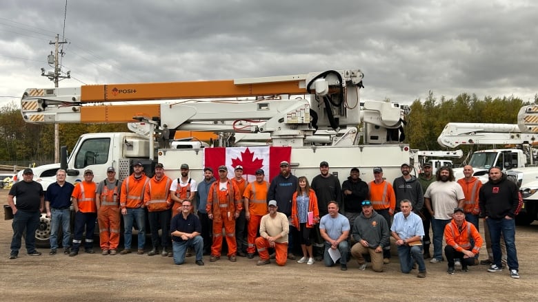 a crew stnds in front of a power truck. 