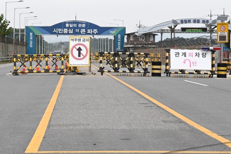 Barricades are shown on a paved road, with Asian language on signs. 