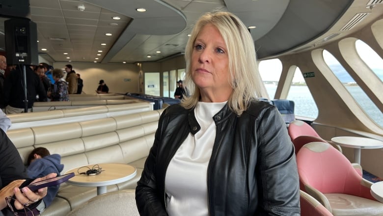 A woman in a black leather jacket standing inside a ferry. 