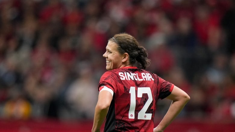 A woman smiles in a red jersey that reads: Sinclair, 12