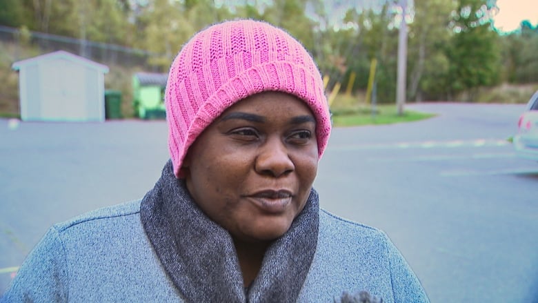 A woman in a pink hat is standing outside of the food bank. 