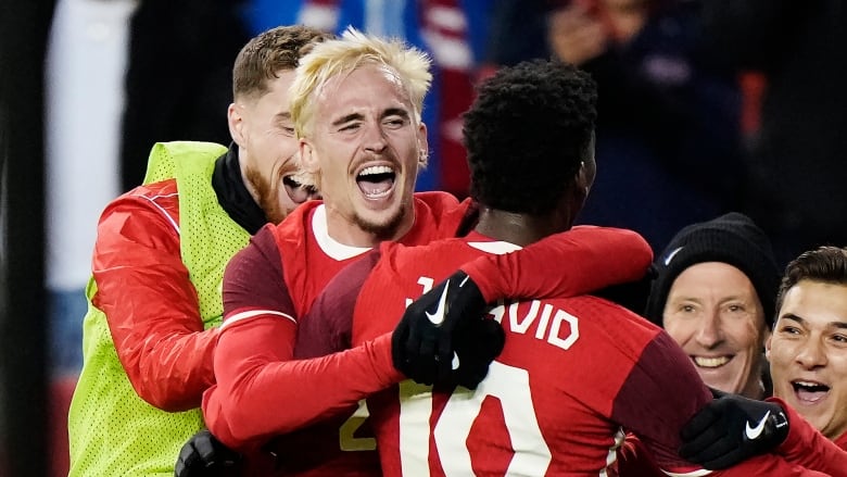 Men's soccer players celebrate a goal.