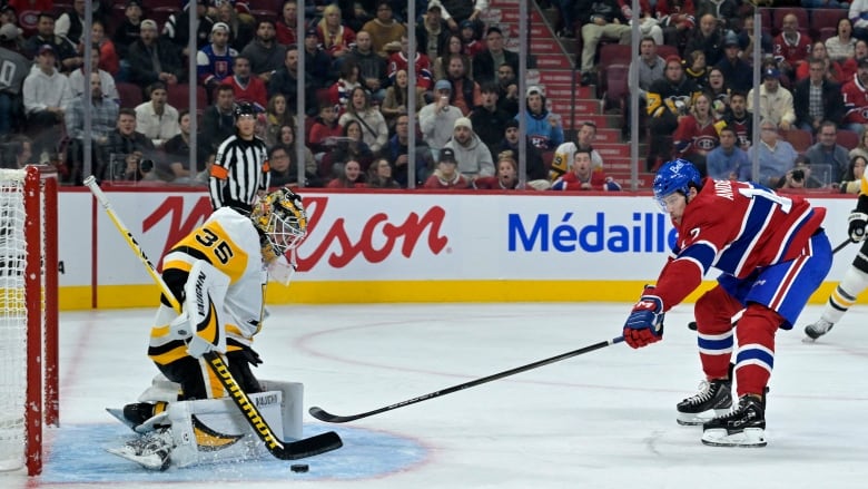 A Montreal Canadiens player lunges at the puck as a Pittsburgh Penguins goaltender fall into the butterfly position.