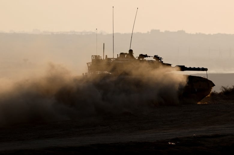 A soldier seen atop a moving tank.