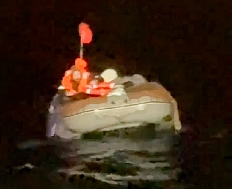 A grain photo of a figure in an inflatable boat in the sea at night