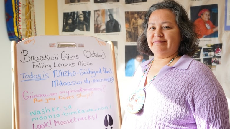 A woman in a classroom standing next to a whiteboard.