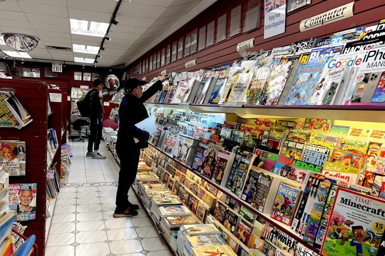 Two men browse a magazine shop. 