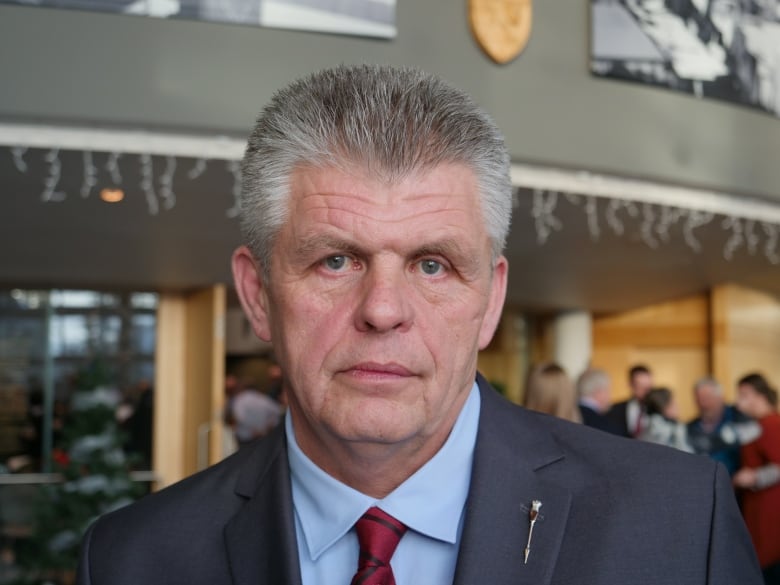 A man with a serious expression wearing a suit.