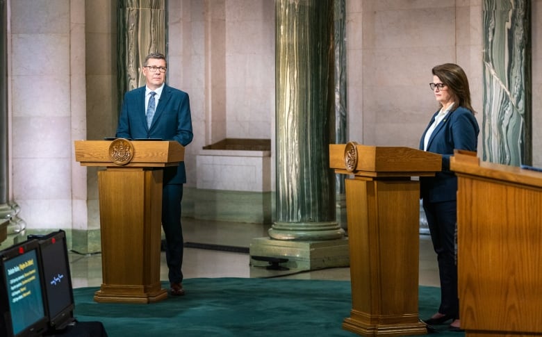 Two people stand at podiums.