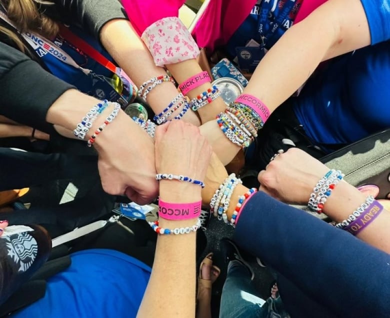 A closeup of multiple people's hands held out toward one another in a circle. All are wearing friendship bracelets. 