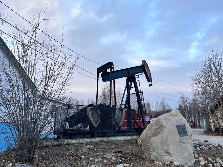 a pump jack against a clouded sky