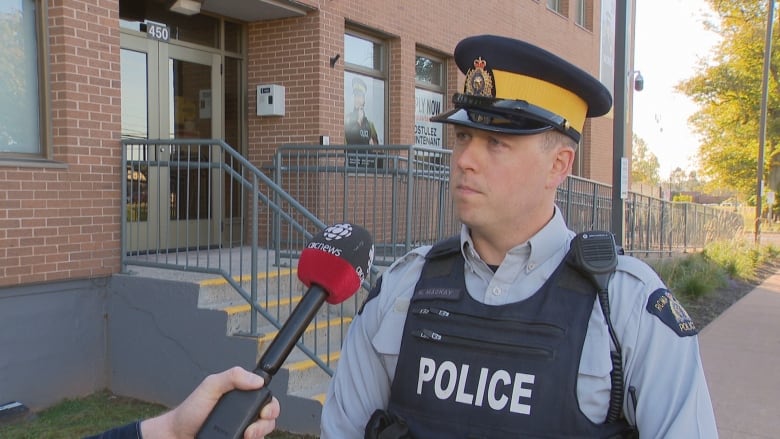 RCMP Const. Kevin MacKay speaking into a microphone in front of the police station.