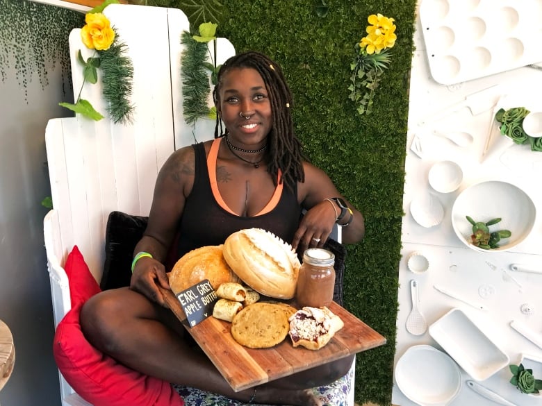 A woman sits crossed legged with a platter of apple butters and bread.