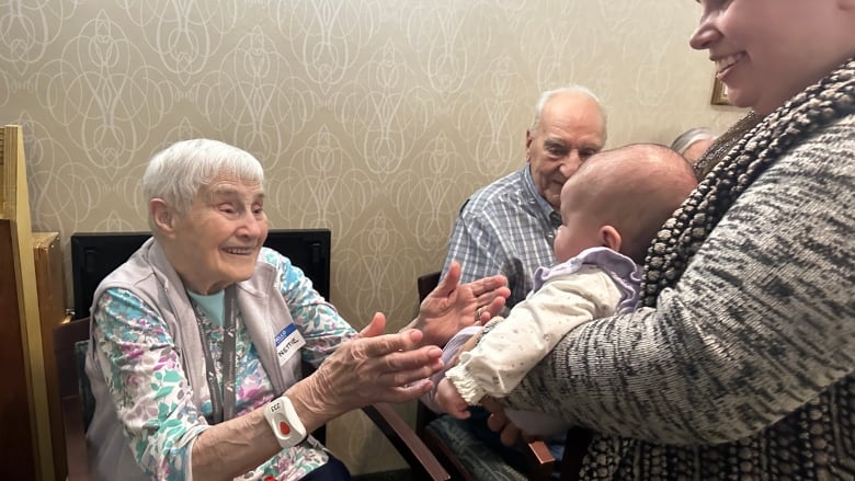 An older woman smiles as she looks at a baby girl.