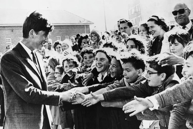 A teen shakes hands with people reaching out to greet them.