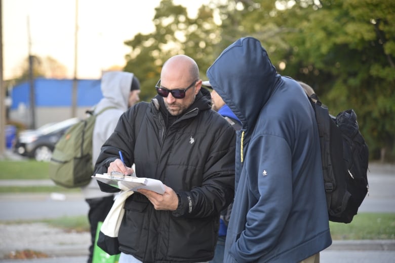 Two men look at a clipboard