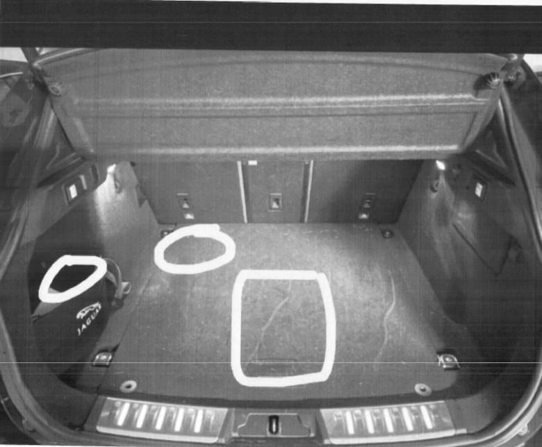 The trunk of a car with three white chalk drawings  one in the form of a box in the middle of the trunk and two in the form of white circles in the left front corner of the trunk.