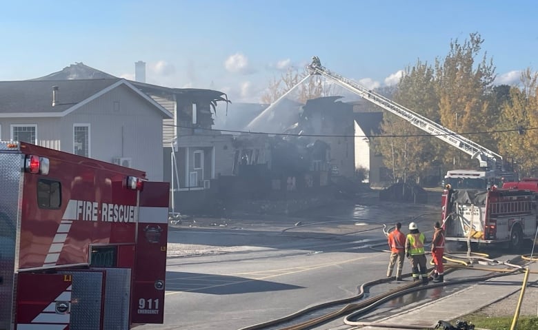 A street with a building missing it's second floor. There is a fire truck spraying water on it.