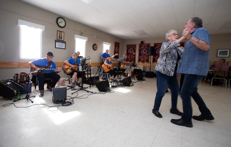 A man and woman dance in front of a band. 