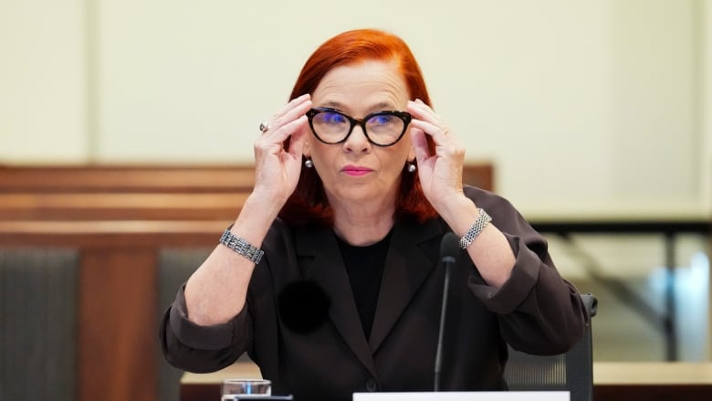 A woman with red hair and black rimmed glasses 