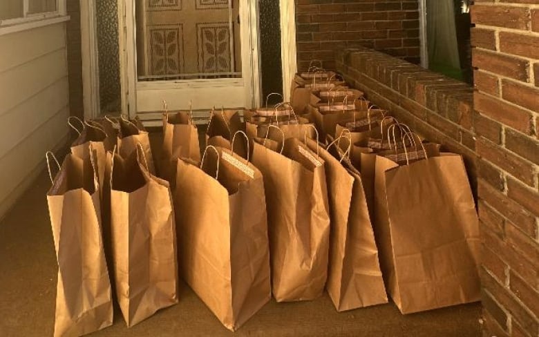 17 paper grocery bags sitting on a doorstep. 