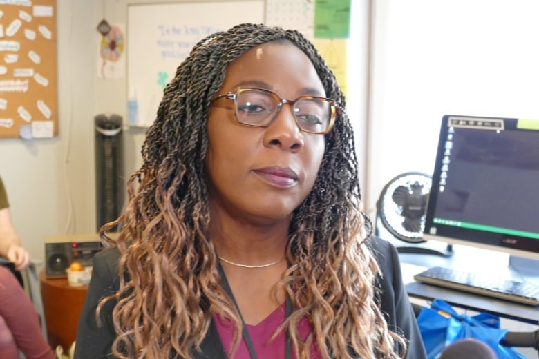 A woman wearing glasses speaks to someone who is off camera. 