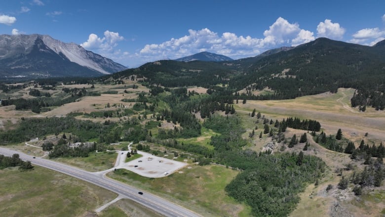 An image from above of a small building off of a highway. Mountains and foothills are in the background of the picture. 