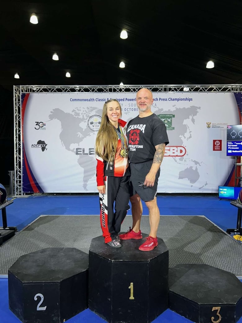 Husband and wife stand on number one podium in sportswear. 